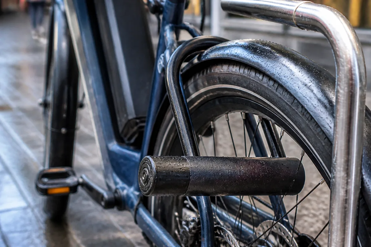 Cadenas en U épais fixant un vélo électrique à un arceau de stationnement urbain